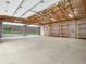 Spacious garage with unfinished walls, high ceilings, a concrete floor, wooden shelves, and an open garage door at 3504 Morgan Oaks Cir, Martinsville, IN 46151