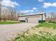 Detached garage with a spacious gravel driveway and additional side entry door on a sunny day at 3504 Morgan Oaks Cir, Martinsville, IN 46151
