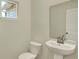 Bright half bathroom with modern pedestal sink, toilet, mirror, and fresh paint, creating a clean look at 4087 Railhead Ave, Westfield, IN 46074