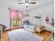 Bright bedroom with a bunk bed, pink curtains, hardwood floors, and a decorative rug at 454 Roberson Blvd, Mooresville, IN 46158