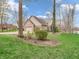 Exterior side view of brick home with large lawn, landscaping, mature trees, lake view and three-car garage at 454 Roberson Blvd, Mooresville, IN 46158