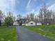 Traditional home showcasing a long driveway, lush lawn, and gray siding, complemented by dark shutters and a black roof at 4560 S 975 E, Zionsville, IN 46077