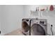 A modern laundry room showcasing gray front load washer and dryer and a shelf for storage at 5374 Marigold Dr, Plainfield, IN 46168