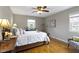 Sunlit bedroom with a queen-size bed, ceiling fan, and hardwood floors, complemented by a decorative armchair at 5420 E 81St St, Indianapolis, IN 46250