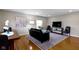 Bright living room featuring hardwood floors, neutral walls, a decorative area rug, and a black sofa at 5420 E 81St St, Indianapolis, IN 46250