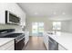 An open-concept kitchen features white cabinets, stainless steel appliances, and a central island with sleek countertops at 5804 Summertree Pl, Whitestown, IN 46052