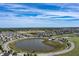 Sweeping aerial view capturing a community layout with a central lake and recreational amenities at 6472 W Treeline Ln, McCordsville, IN 46055