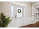 Elegant front door with glass panels and a wreath, complemented by a decorative plant and gleaming hardwood floors at 6472 W Treeline Ln, McCordsville, IN 46055