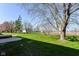 A large backyard features green grass, mature trees, and plenty of open space for outdoor activities at 718 Marie Ln, Fortville, IN 46040