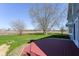 View from a red wood deck overlooking the large lawn and trees with a field and horizon in the distance at 718 Marie Ln, Fortville, IN 46040