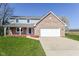 Charming two-story home features a brick facade, attached two-car garage, front porch, and a well-maintained lawn at 718 Marie Ln, Fortville, IN 46040