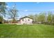 Well-manicured backyard with lush green grass, a deck, and mature trees providing shade at 7482 N Maple Dr, Frankton, IN 46044