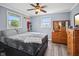 Comfortable bedroom with a queen-sized bed, ceiling fan, hardwood floors, and two large, natural light windows at 7482 N Maple Dr, Frankton, IN 46044