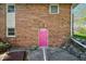 Pink door on brick exterior of home, adding a pop of color to the exterior and landscaping at 7482 N Maple Dr, Frankton, IN 46044