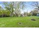Expansive backyard with a large grassy area, mature trees, and a rustic fire pit at 7709 Lewis Rd, Indianapolis, IN 46256
