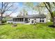 Back exterior of house with sunroom, a green yard, and fire pit, creating inviting outdoor space at 7709 Lewis Rd, Indianapolis, IN 46256