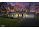 Charming single-story home with a well-manicured lawn, cozy porch, and attached garage at sunset at 7709 Lewis Rd, Indianapolis, IN 46256