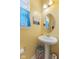 Cozy powder room featuring a pedestal sink, decorative mirror, and bright yellow walls at 8158 Wheatfield Ct, Camby, IN 46113