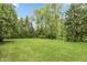 Large green backyard with trees, green grass, and a fence in the distance at 8535 Washington Blvd, Indianapolis, IN 46240