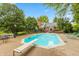 Backyard pool and patio, surrounded by green trees and landscaping and blue sky on a sunny day at 8535 Washington Blvd, Indianapolis, IN 46240