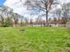 Large green backyard with mature trees, perimeter fence, and tan-sided home with deck at 8621 Manderley Dr, Indianapolis, IN 46240