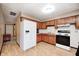 Functional kitchen features white appliances, wooden cabinets, vinyl flooring and tiled backsplash, perfect for cooking at 9055 Panorama Ct, Indianapolis, IN 46234