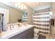 Modern bathroom with double sinks and vanity with shower and tub combination behind a striped curtain at 9812 Logan Ln, Fishers, IN 46037