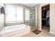 Bright bathroom featuring a soaking tub, glass enclosed shower, and walk in closet at 9812 Logan Ln, Fishers, IN 46037