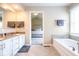 Bright bathroom with double vanity, soaking tub, tile floors, and a view to the bedroom at 9812 Logan Ln, Fishers, IN 46037
