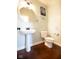 Stylish powder room featuring a pedestal sink with a round mirror and dark wood floors at 1060 Cape Coral Dr, Cicero, IN 46034