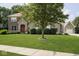 Charming brick and stone home with a vibrant red door, surrounded by a lush green lawn and manicured landscaping at 1060 Cape Coral Dr, Cicero, IN 46034