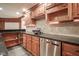 Finished basement wet bar with rich wood cabinetry, granite counters, stainless dishwasher, and tile backsplash at 10628 Walnut Creek W Dr, Carmel, IN 46032