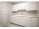 Bright laundry room features ample white cabinetry, countertops, sink and light gray tiled floors at 10628 Walnut Creek W Dr, Carmel, IN 46032