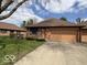 Brick exterior with lush green lawn, landscaping, paved driveway, and attached single car garage at 1215 Willow Springs Blvd, Brownsburg, IN 46112