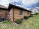 Side view of brick home and yard including satellite dish, bushes and air conditioning unit at 1215 Willow Springs Blvd, Brownsburg, IN 46112