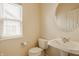 Well-lit bathroom with a pedestal sink, a round mirror, and a window with blinds at 12561 Gladecrest Dr, Carmel, IN 46033