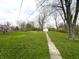 Expansive backyard featuring a pathway leading to a storage shed surrounded by mature trees at 129 S Boehning St, Indianapolis, IN 46219