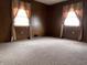 Inviting bedroom with wood paneled walls, neutral carpeting, and ample natural light from two windows at 129 S Boehning St, Indianapolis, IN 46219