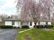 Charming home featuring a blooming tree, lush lawn, and trimmed hedges enhancing the curb appeal at 129 S Boehning St, Indianapolis, IN 46219
