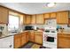 Cozy kitchen featuring wood cabinets, white appliances, and a window view at 13346 N Miller Dr, Camby, IN 46113