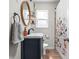 Well-lit bathroom features a navy vanity, decorative oval mirror, and shower with a floral curtain at 1355 E 56Th St, Indianapolis, IN 46220