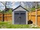 Well-maintained gray shed with double doors, nestled in a verdant backyard with a wooden privacy fence at 1355 E 56Th St, Indianapolis, IN 46220