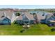 Aerial view of a home with manicured lawn, stone patio and community pond at 15150 Mooring E Cir, Carmel, IN 46033