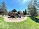 Well-maintained playground area with a wooden playset, slide, and surrounding green space at 15150 Mooring E Cir, Carmel, IN 46033