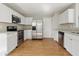 Modern kitchen featuring white cabinets, stainless steel appliances, and wood-look flooring at 18904 Planer Dr, Noblesville, IN 46062