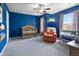 A cozy Bedroom with blue walls, a wooden crib, a comfortable armchair, and ample natural light streaming through the windows at 3038 Arrowroot Ln, Indianapolis, IN 46239