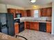 Efficient kitchen features wood cabinets, modern black appliances, and a tile floor for easy cleaning and maintenance at 3097 Limber Pine Dr, Whiteland, IN 46184