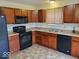 Efficient kitchen features wood cabinets, modern black appliances, and a tile floor for easy cleaning and maintenance at 3097 Limber Pine Dr, Whiteland, IN 46184