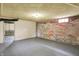 Unfinished basement features painted brick accent wall, painted floor and access to another room at 3140 N Washington Blvd, Indianapolis, IN 46205