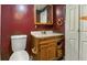 Bathroom featuring red walls, sink and toilet; storage cabinet, and light wood trim at 3346 S Lockburn St, Indianapolis, IN 46221